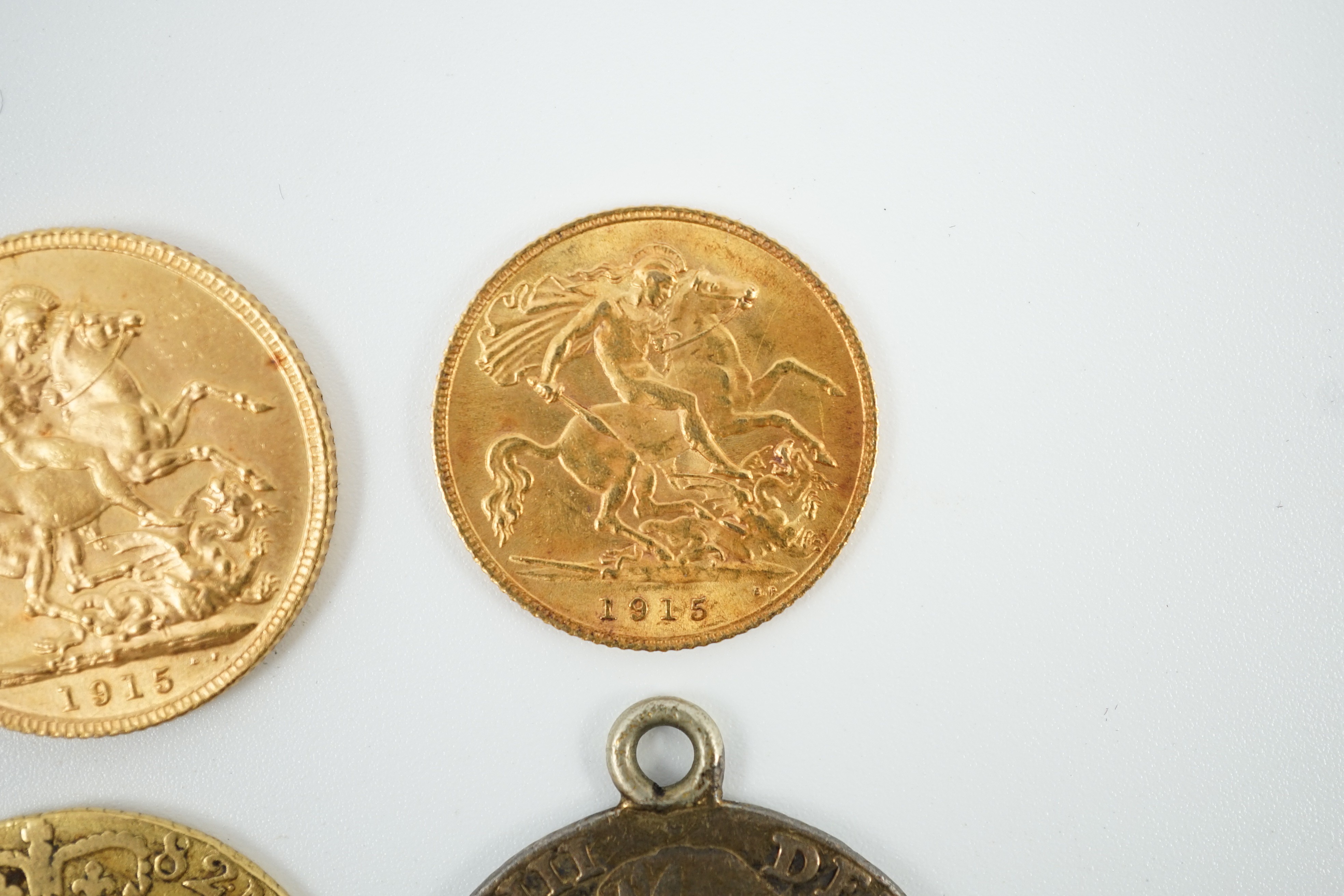 A George V 1915 gold sovereign and a 1915 gold half sovereign, a George III 1782 gold guinea(worn) and a George III 1787 shilling, with pendant mount.